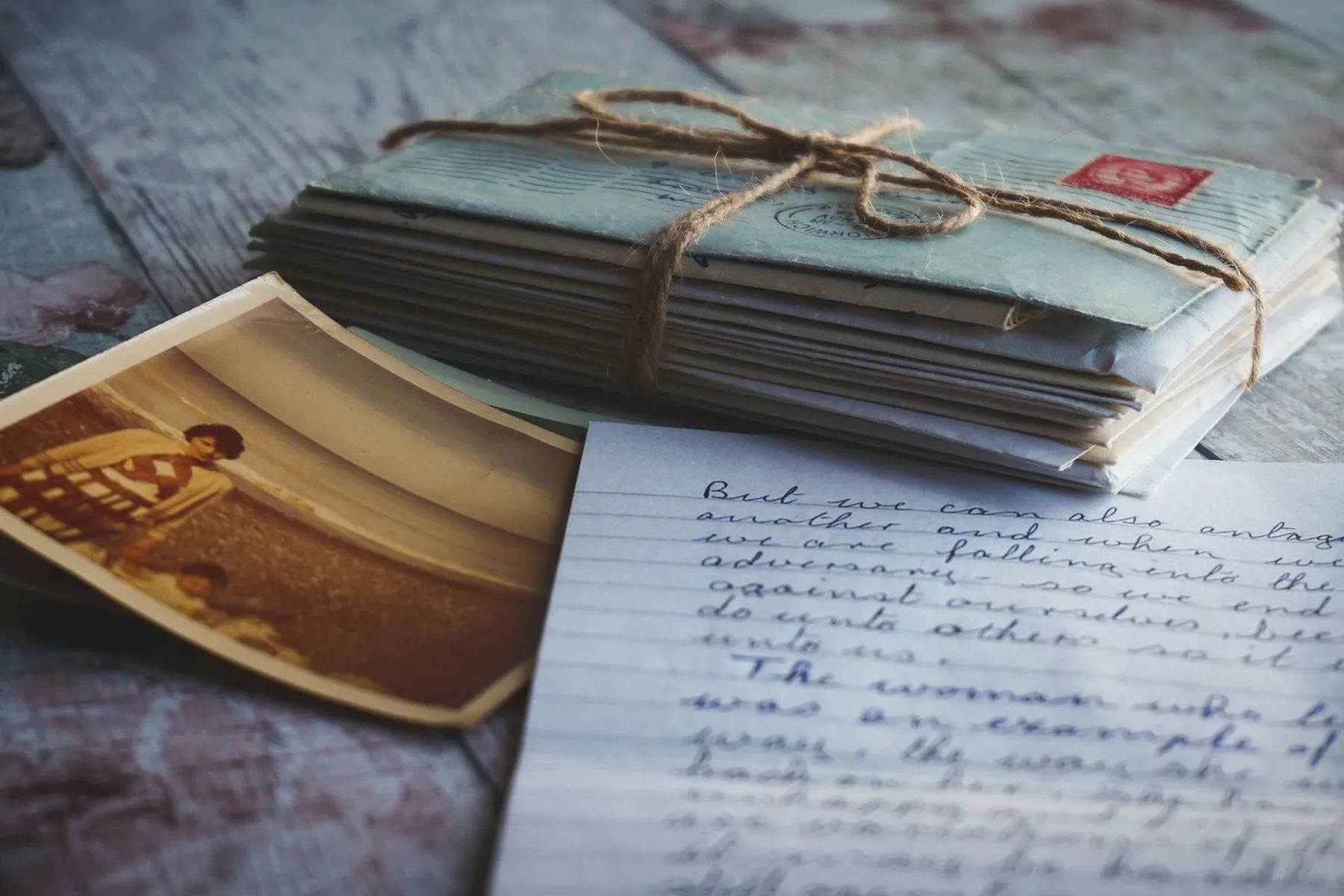 A bundle of old letters tied with twine beside a handwritten note and a faded photograph