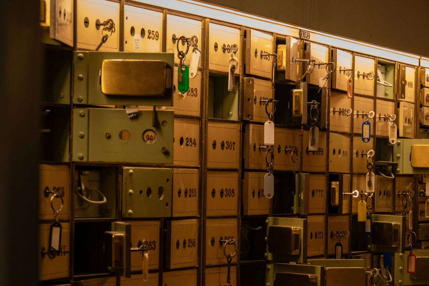 A wall of old numbered safe deposit boxes with keys still hanging in the locks
