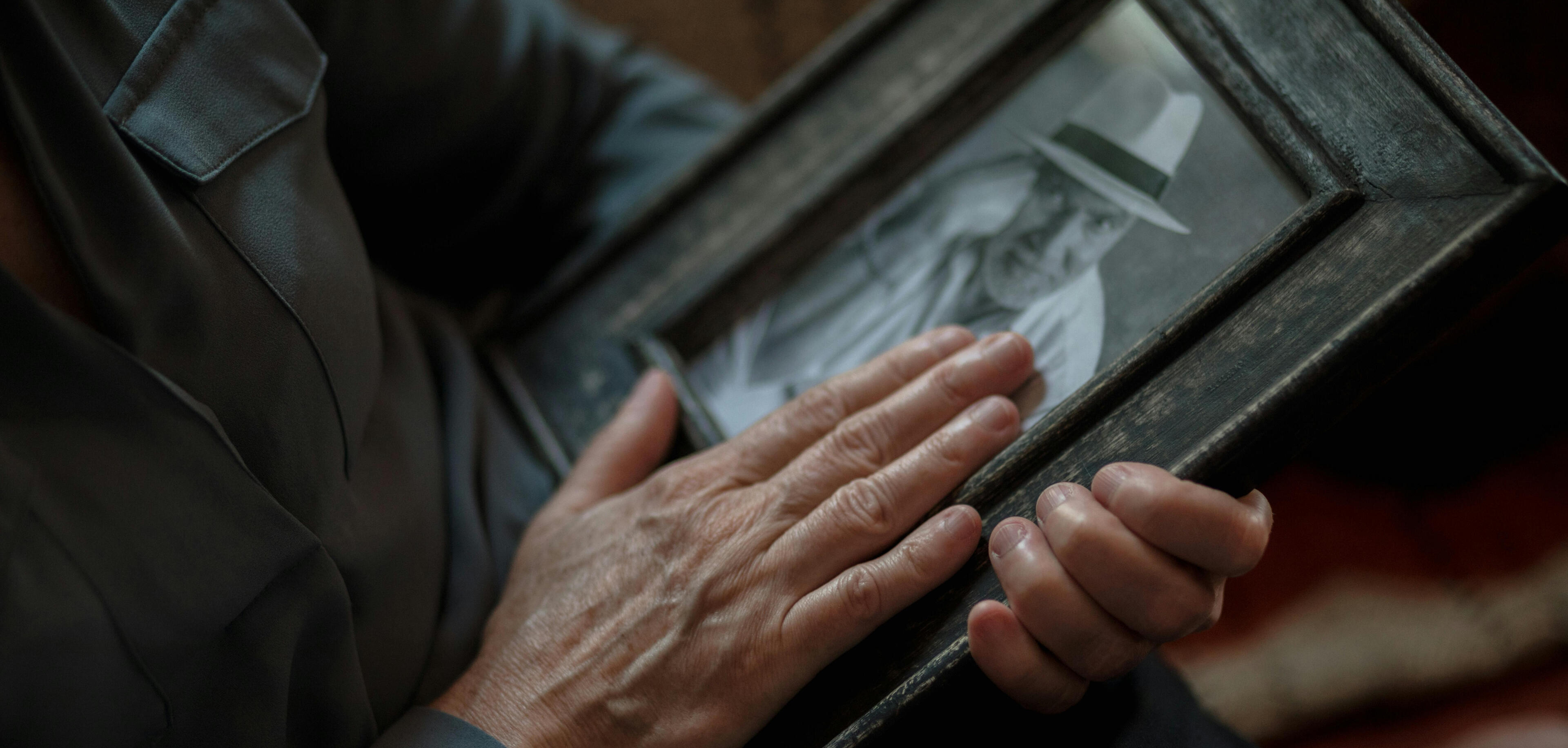 Close-up of hands holding a framed black-and-white family portrait, suggesting memory, legacy, and continuity planning.